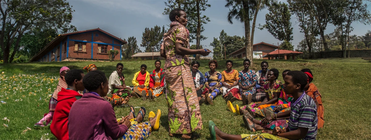 African woman speaks to women seated around her